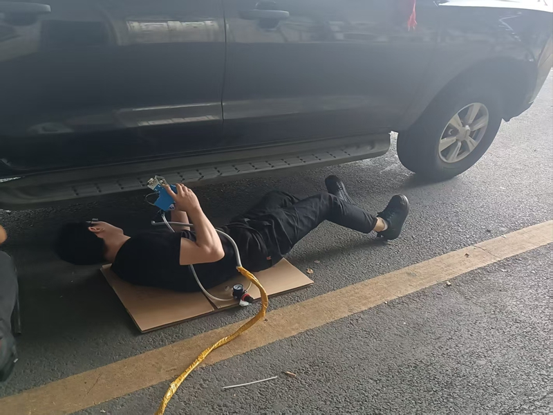 车服部员工俯身躺车底精准作业